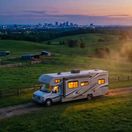Campfire in the night sky with RV in the background
