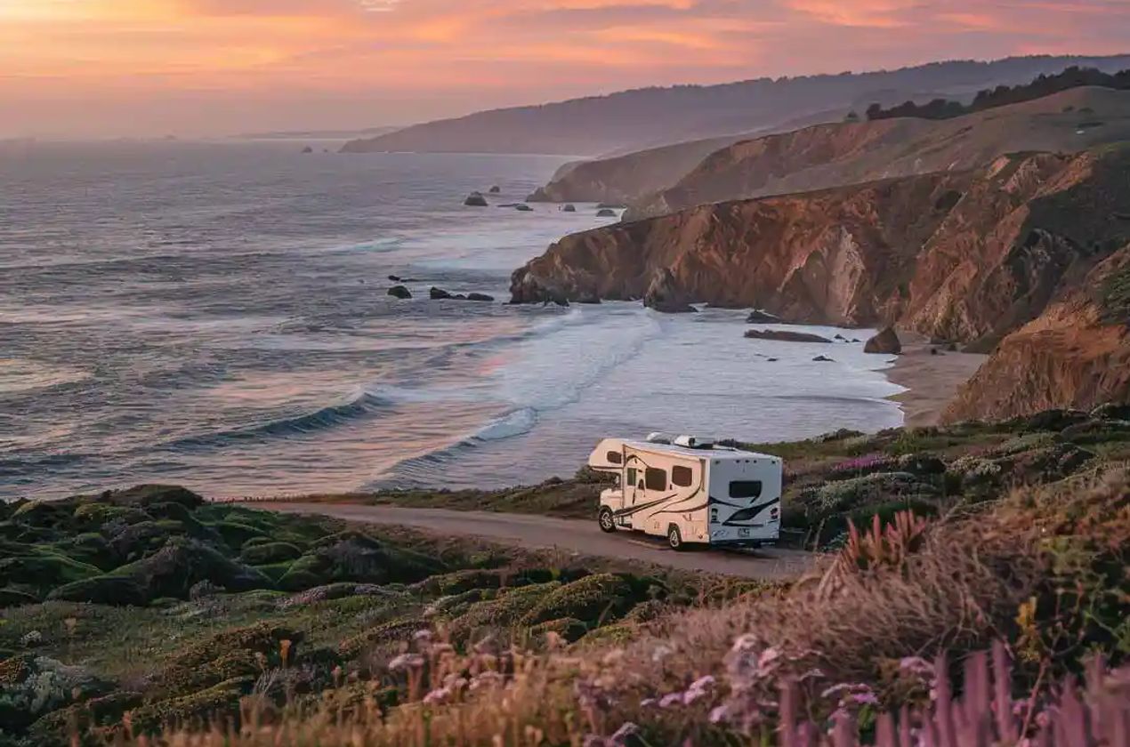 RV parked overlooking beautiful coastal scenery during golden hour.