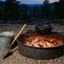 Fire pit for camping with a bucket of water next to it.
