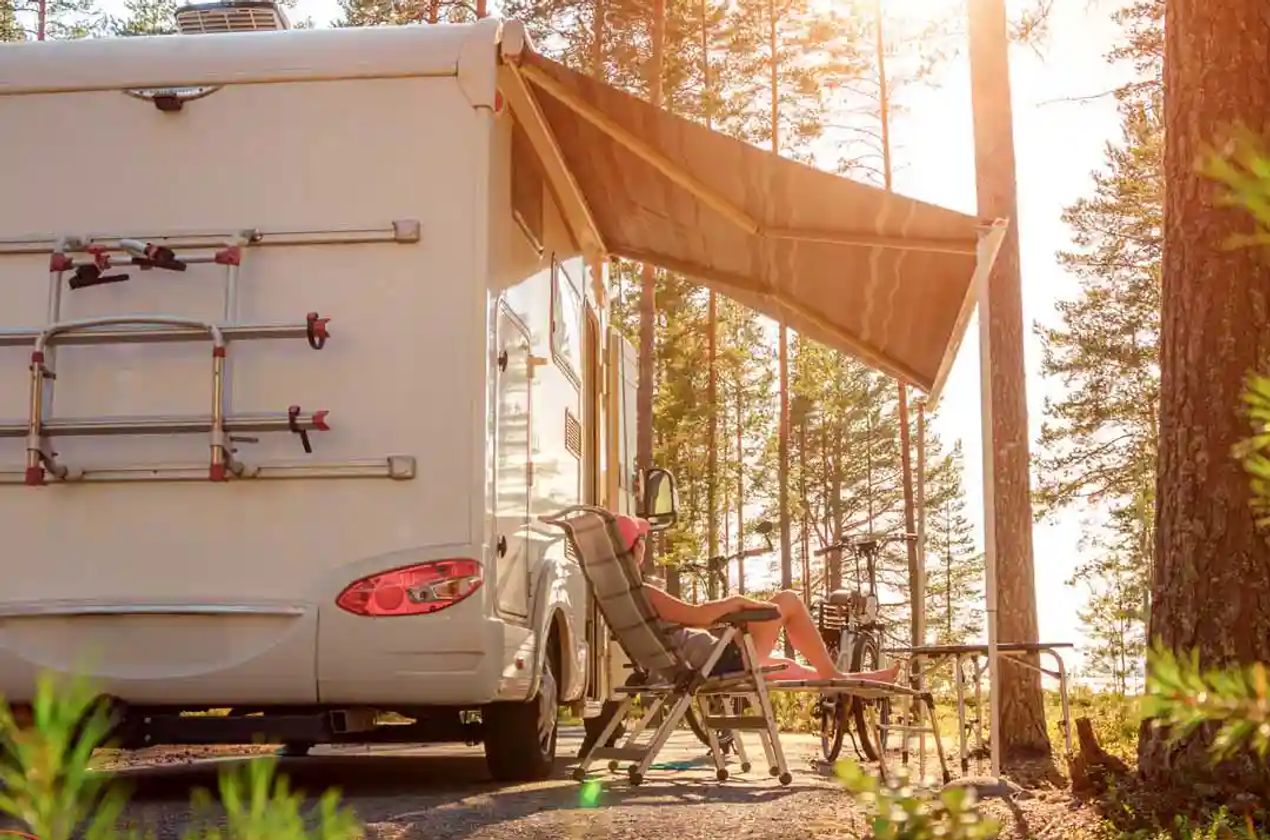 Lady enjoying her RV camping in a wooded area.