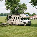 Class B RV parked in a pasture near a picnic table