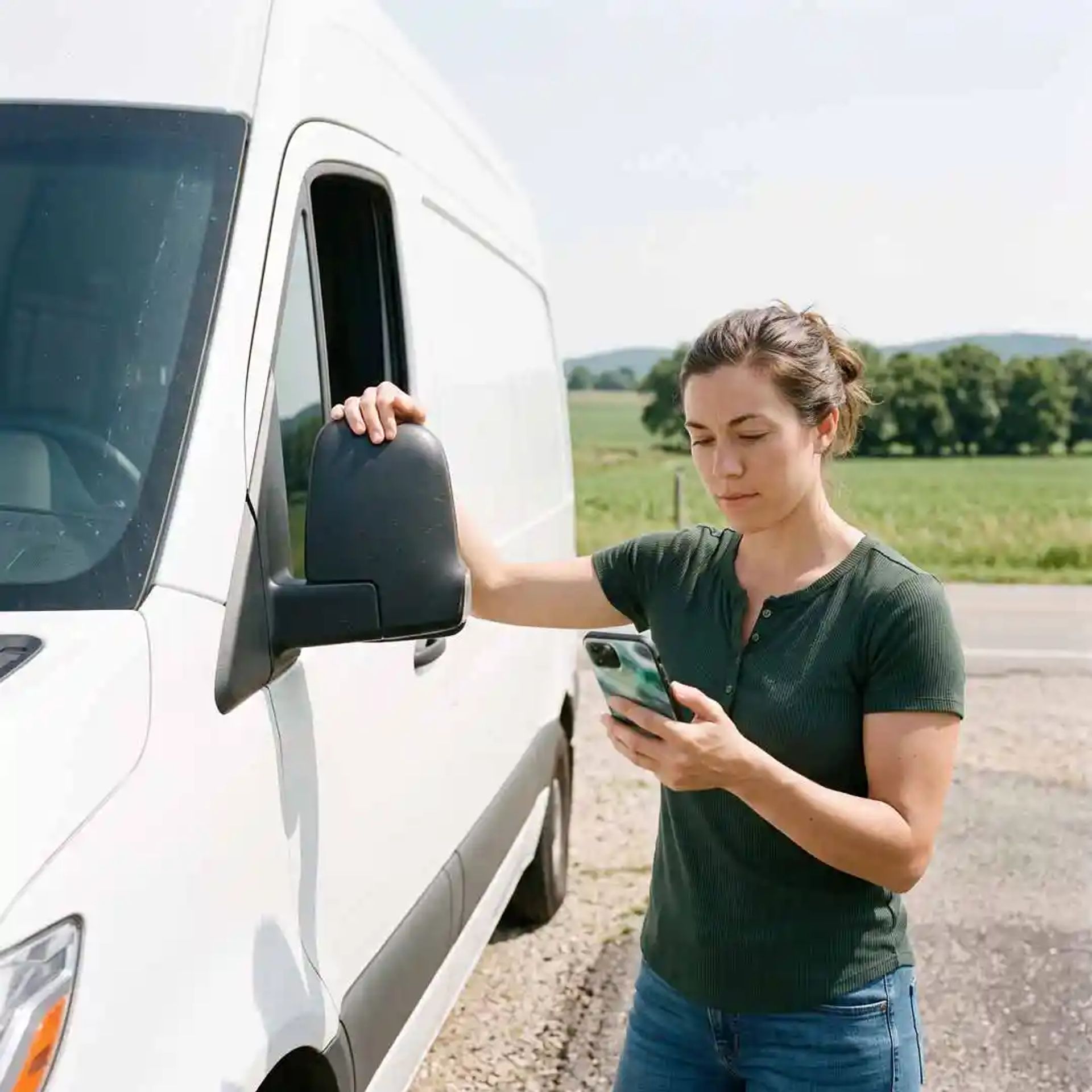 Young woman near her camper RV, checking her phone.
